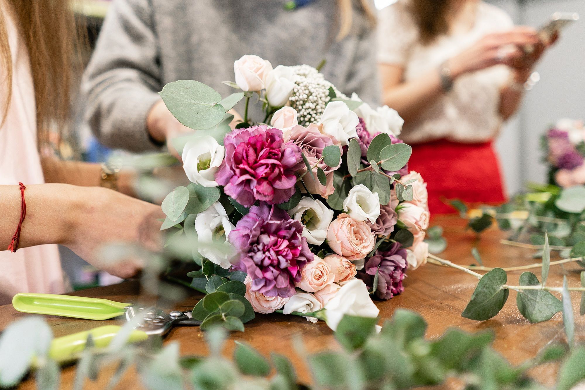 Eine Frau bindet einen Strauß Blumen auf einem Tisch zusammen